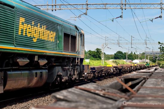 freightliner locomotive in green and yellow against a blue sky