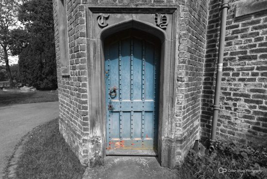 An old blue door in a mostly black and white image