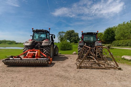 Two farm tractors in a field with blue sky