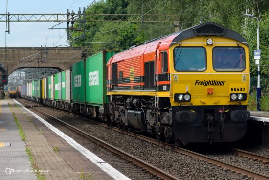 A train of brightly colored containers headed by an orange and yellow locomotive.