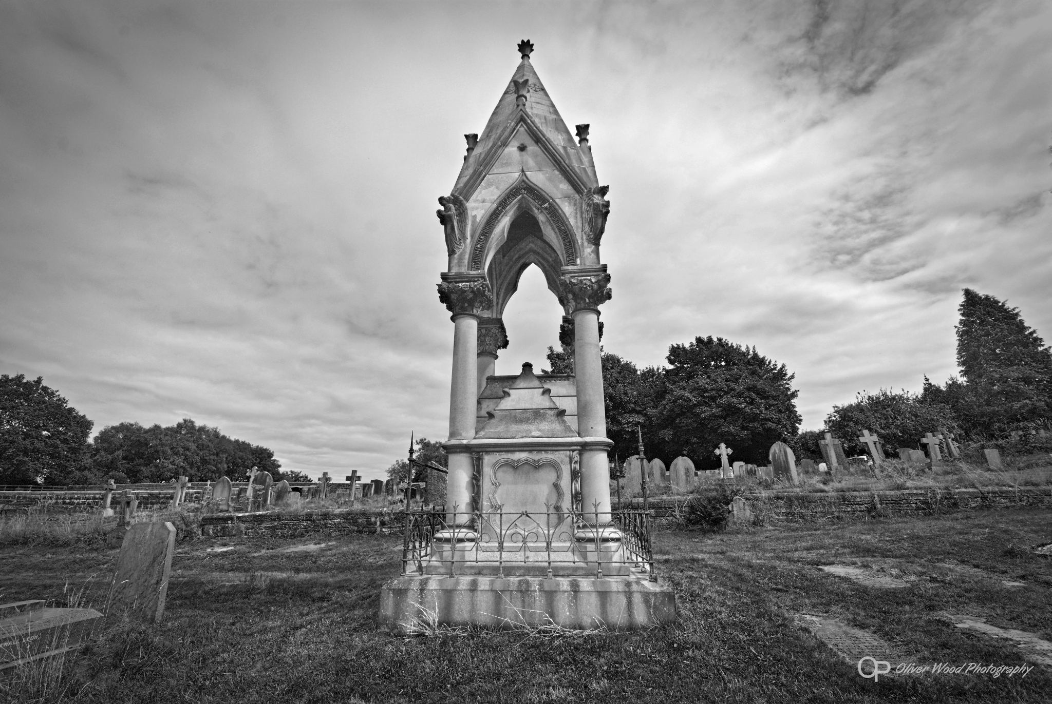 Black and white image of a stone monument in graveyard