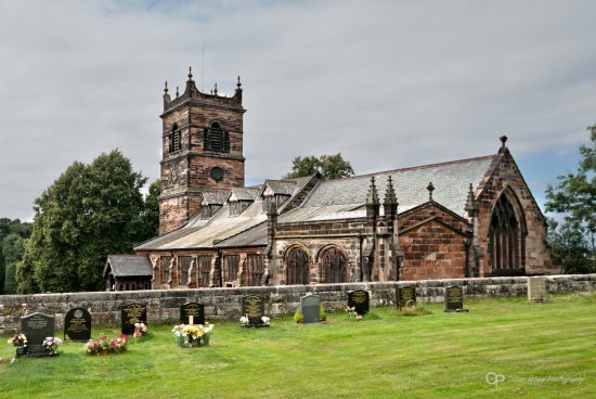 A photo of an old church with green grass in the foreground.